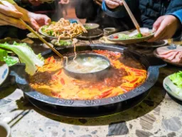 Klasyczny chiński hotpot – wspólne przygotowywanie posiłków przy stole w gotującym się bulionie Klasyczny chiński hotpot – wspólne przygotowywanie posiłków przy stole w gotującym się bulionie